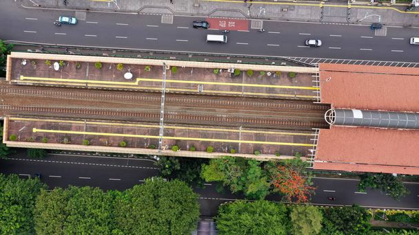 Letecký dron shora pohled na dojíždějící trať KRL Jabodetabek s elektrickým vlakem JR205 na trati Dipo Depok Depot, Západní Jáva, Indonésie. - Fotografie, Obrázek