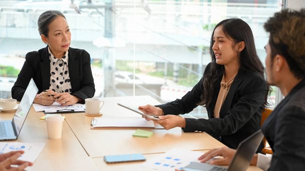 Egy komoly céges üzleti találkozó imidzse, egy stresszes, vezető női főnök figyelmesen hallgatja egy Y-generációs női menedzser üzleti tervét.. - Fotó, kép