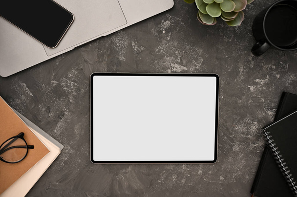 Dijital tablet dokunmatik beyaz ekran modeli ve gri arkaplanda grunge çimento dokusu üzerine ofis aksesuarları. Modern çalışma alanı konsepti. Üst görünüm, düz uzanma - Fotoğraf, Görsel