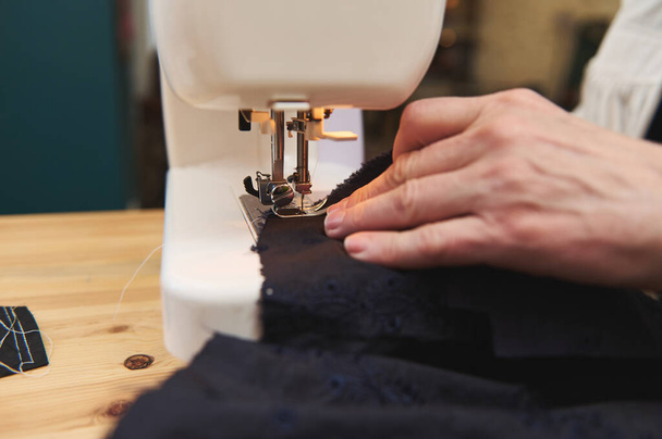 Yksityiskohta naisten kädet takana hänen ompelu ompelukone samalla luoda käsintehty kokoelma uusia vaatteita. Räätälöinti, muoti vaatteet suunnittelu liiketoimintaa - Valokuva, kuva