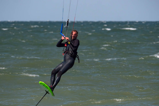 Homem Kite Foil Surfista com barba e cabelos longos no mar. Foto de alta qualidade - Foto, Imagem