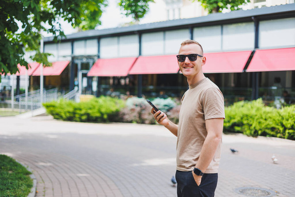 Hombre de compras. Hombre sonriente con bolsas de compras caminando por la calle. Consumismo, concepto de estilo de vida - Foto, imagen