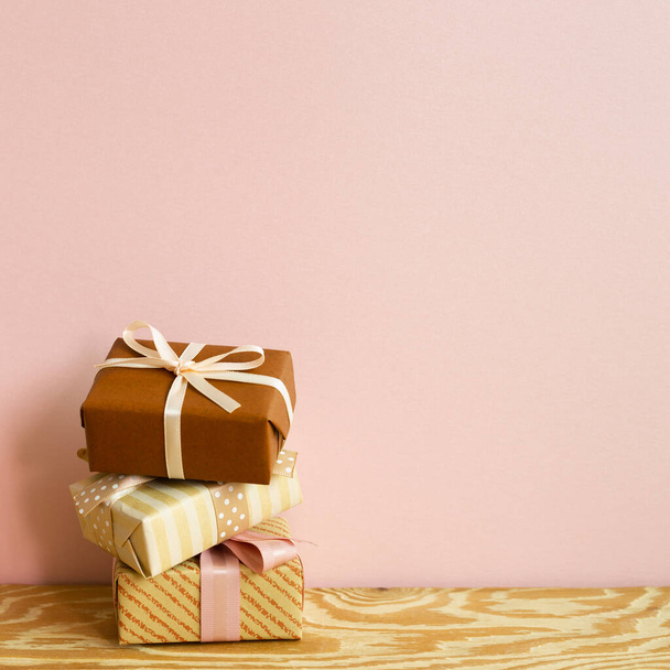 Καφέ κουτιά δώρου σε ξύλινο τραπέζι. Ροζ φόντο στον τοίχο. αντίγραφο χώρου - Φωτογραφία, εικόνα
