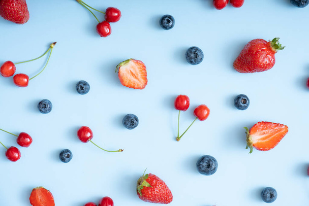 Pattern with strawberries, cherries and raspberries on a blue background. - Fotó, kép