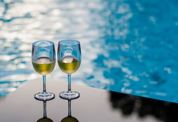 Two glasses of white wine put on table at swimming pool for Holiday and summer drink concept. - Foto, immagini