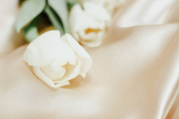 Bouquet of white tulips on silk golden nude satin background. - Foto, immagini