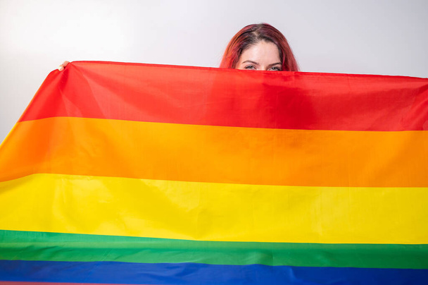 Caucasian woman holding lgbt flag covering herself - 写真・画像