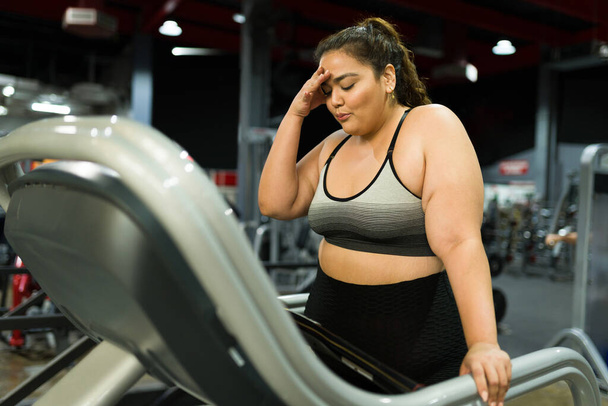 Müde Frau mit Fettleibigkeit fühlt sich erschöpft und macht Pause vom Laufen auf dem Laufband im Fitnessstudio  - Foto, Bild