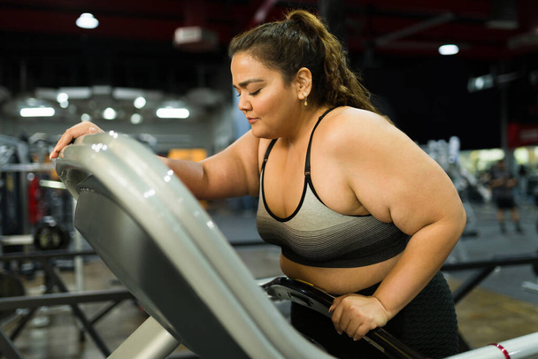 Erschöpfte dicke Frau fühlt sich nach Laufen und Cardio-Workout im Fitnessstudio krank und übel - Foto, Bild