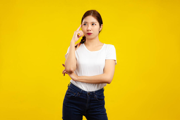 Portrait of Asian Woman thinking over isolated yellow background, fashion and lifestyle people concept - Zdjęcie, obraz