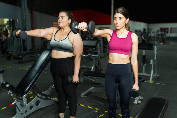 Gyönyörű fitness edző tréning egy plusz méretű nővel. Személyi edző edz egy elhízott nővel. - Fotó, kép