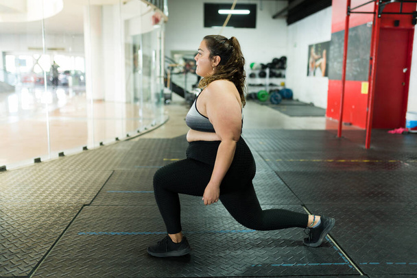 Mulher ativa com obesidade exercitando e fazendo lunges no ginásio. Mulher com excesso de peso com um estilo de vida fitness - Foto, Imagem