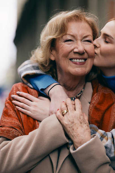 Une grand-mère et une petite-fille heureuses embrassant et embrassant dehors. - Photo, image