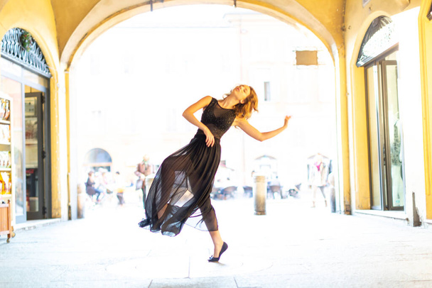 krásná italská brunetka dívka tančí v centru Reggio Emilia v uličkách s dlouhou sukní. Kvalitní fotografie - Fotografie, Obrázek