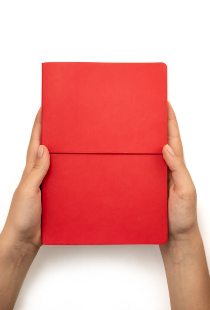 Beyaz zemin üzerinde boş kapağı olan kırmızı kitabı tutan kadın eller, üst görünüm - Fotoğraf, Görsel