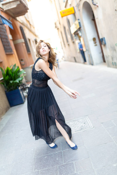 hermosa chica morena italiana baila en el centro de Reggio Emilia en los callejones con falda larga. Foto de alta calidad - Foto, Imagen
