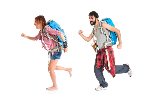 Jonge backpacker lopen op witte achtergrond - Foto, afbeelding