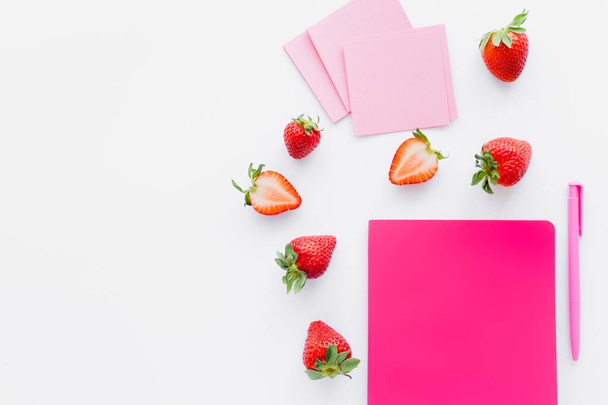 Top view of ripe strawberries near notebook and sticky notes on white background - Φωτογραφία, εικόνα