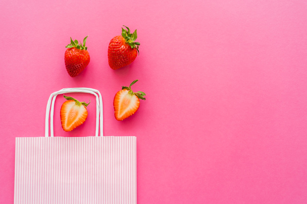 Top view of fresh strawberries near shopping bag on pink background  - Photo, image