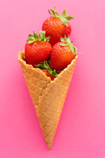 Top view of juicy strawberries in waffle cone on pink background  - Foto, afbeelding
