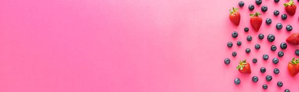 Byt ležel s jahodami a celé borůvky na růžovém pozadí, prapor  - Fotografie, Obrázek