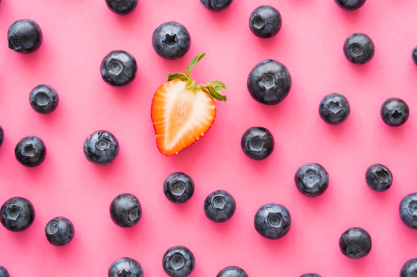 Flat lay of cut strawberry near blueberries on pink background  - Foto, afbeelding