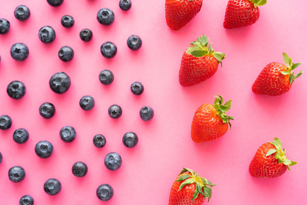 flat lay of juicy blueberries near strawberries on pink background  - Fotó, kép