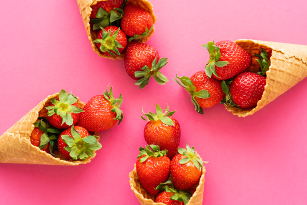 Flat lay with delicious waffle cones with strawberries on pink background  - Photo, Image
