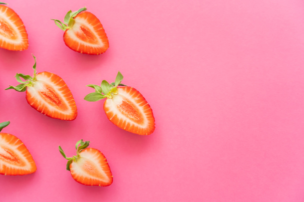 Flat lay of cut fresh strawberries on pink background  - Фото, зображення