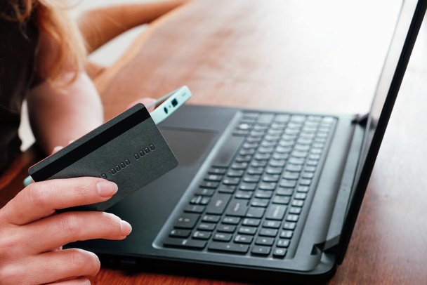 Kobieta z laptopem i kartą kredytową w domu. Płatności online, bankowość cyfrowa. zbliżenie dziewczyny ręce zakup online ze smartfonem, laptopem i kartą kredytową - Zdjęcie, obraz