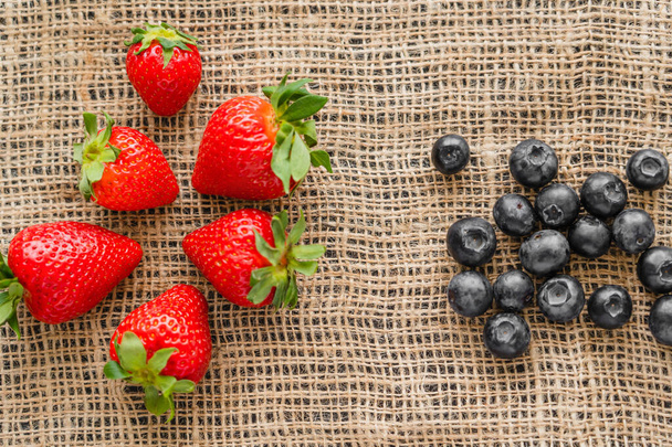 Top view of ripe strawberries and blueberries on sackcloth - Foto, Imagen