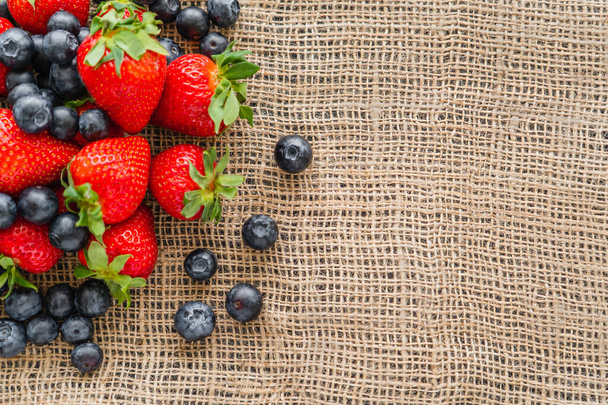 Top view of strawberries and fresh blueberries on sackcloth - Photo, Image