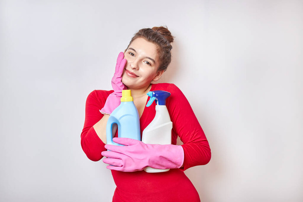 Hermosa chica en una camisa roja sostiene detergentes. - Foto, Imagen