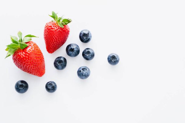 Top view of fresh blueberries and strawberries on white background - Фото, изображение