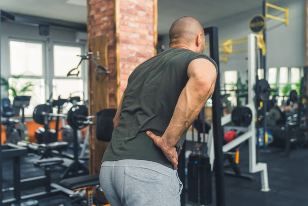 Un hombre se lastimó la espalda durante un entrenamiento en el gimnasio - Foto, imagen