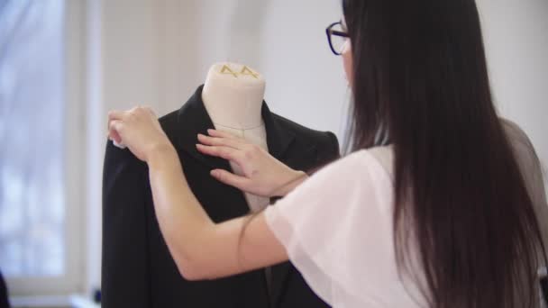 Una joven limpia una chaqueta negra en un maniquí - Imágenes, Vídeo