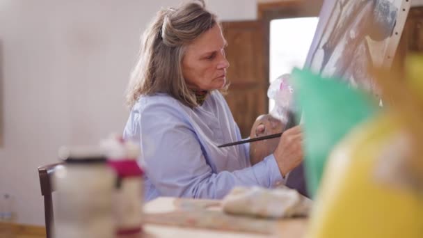 Olgun sanatçı kadın atölyesinde resim yapıyor. - Video, Çekim