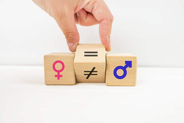 Simbolo di uguaglianza di genere. La mano ruota il cubo e cambia il segno di disuguaglianza in un segno uguale tra i simboli di uomini e donne. Spazio per la copia. - Foto, immagini