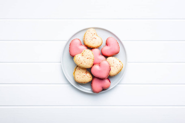 Heart shaped Sweet macarons on plate on a white table. Top view. - Photo, Image