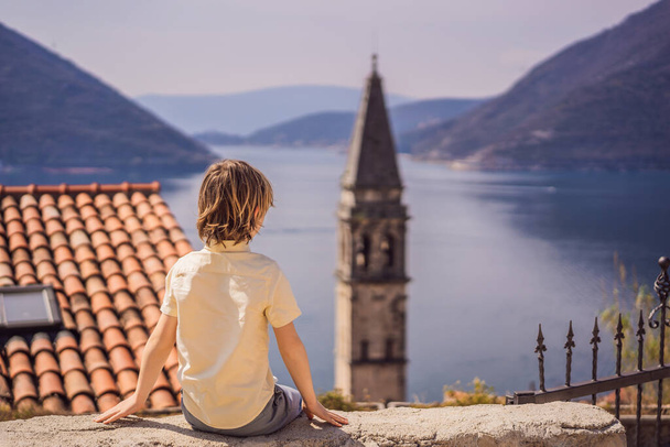 Boy tourist enjoying Colorful street in Old town of Perast on a sunny day, Montenegro. Travel to Montenegro concept. Scenic panorama view of the historic town of Perast at famous Bay of Kotor on a - Foto, imagen