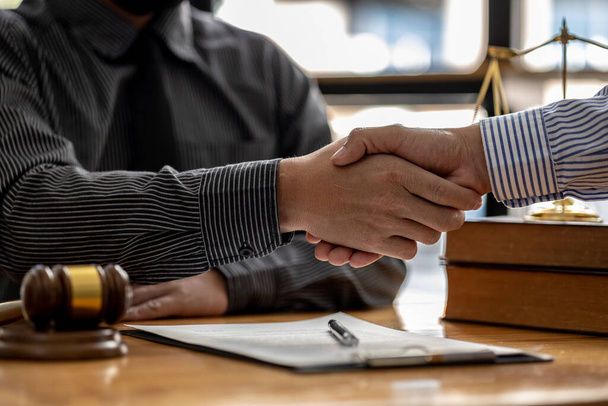 Lawyers shake hands with clients who come to testify in the case of embezzlement from business partners who jointly invest in the business. The concept of hiring a lawyer for legal proceedings. - 写真・画像