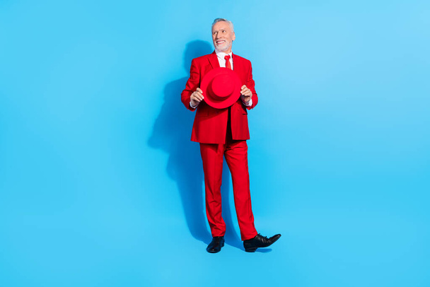 Photo of dreamy inspired pensioner man look empty space hold hat wear red suit shoes isolated blue color background. - Fotoğraf, Görsel
