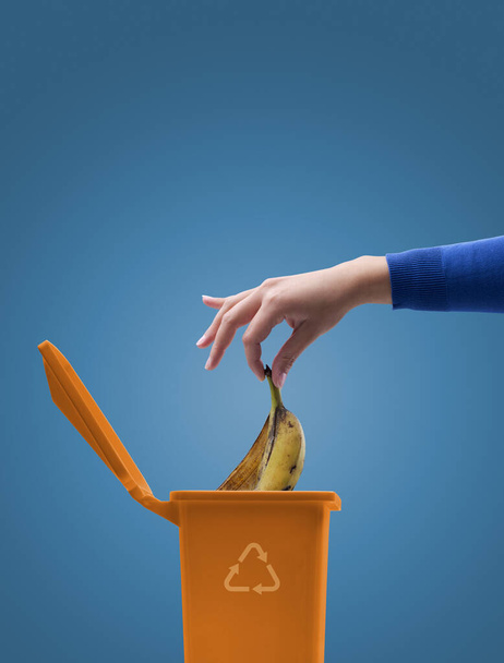 Woman putting biodegradable organic waste in a bin, separate waste collection and recycling concept - Фото, зображення