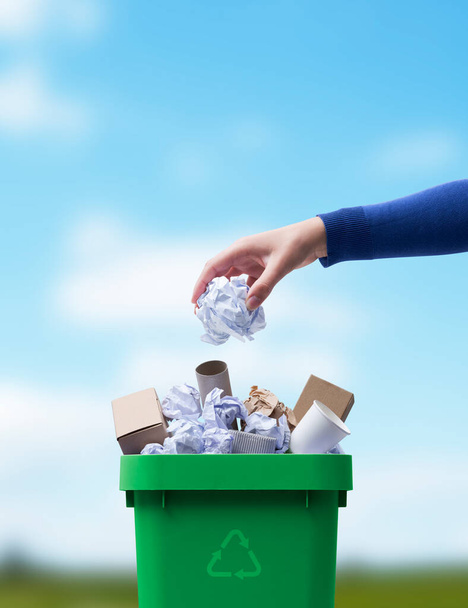 Frau wirft Papier in den Mülleimer, getrennte Müllabfuhr und Recyclingkonzept - Foto, Bild