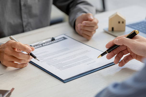 Rental company employee is discussing the details before the customer agrees to sign a rental contract, explaining the details and the terms and conditions of the rental. Real estate rental ideas. - Photo, Image