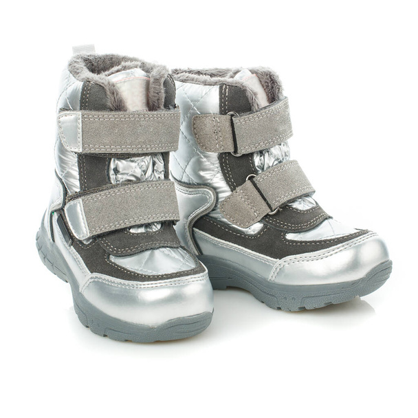 Zbliżenie dzieci ciepłe jasne zimowe buty dla dziewczyny w kolorze srebrnym izolowane na białym tle. Zdjęcia do stron internetowych firm sprzedających obuwie i odzież oraz serwisy e-commerce. - Zdjęcie, obraz