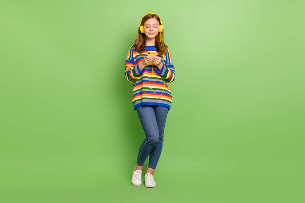 Full length body size view of attractive focused girl listening hit using device gadget chatting isolated on shine green color background. - Fotó, kép