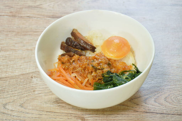  Bibimbub koreanisches Essen Reisbelag eingelegtes Sesamöl Kohl mit Scheiben Karotten und Pilzdressing hacken Huhn in Sauce Paar Ei auf Schüssel - Foto, Bild