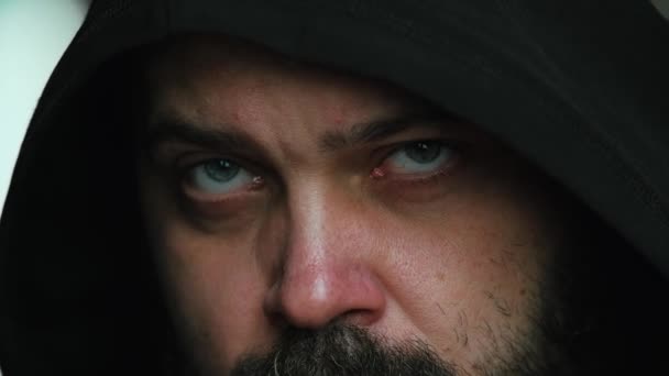 Ein Mann mit Bart auf der Kapuze blickt traurig in die Kamera, statische Kamera, Nahaufnahme des Gesichts - Filmmaterial, Video