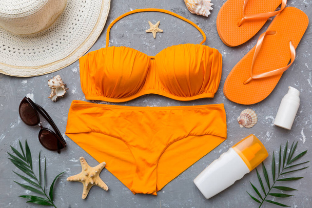 Woman swimwear and beach accessories flat lay top view on colored background Summer travel concept. bikini swimsuit, straw hat and seasheels. Copy space Top view. - Photo, image